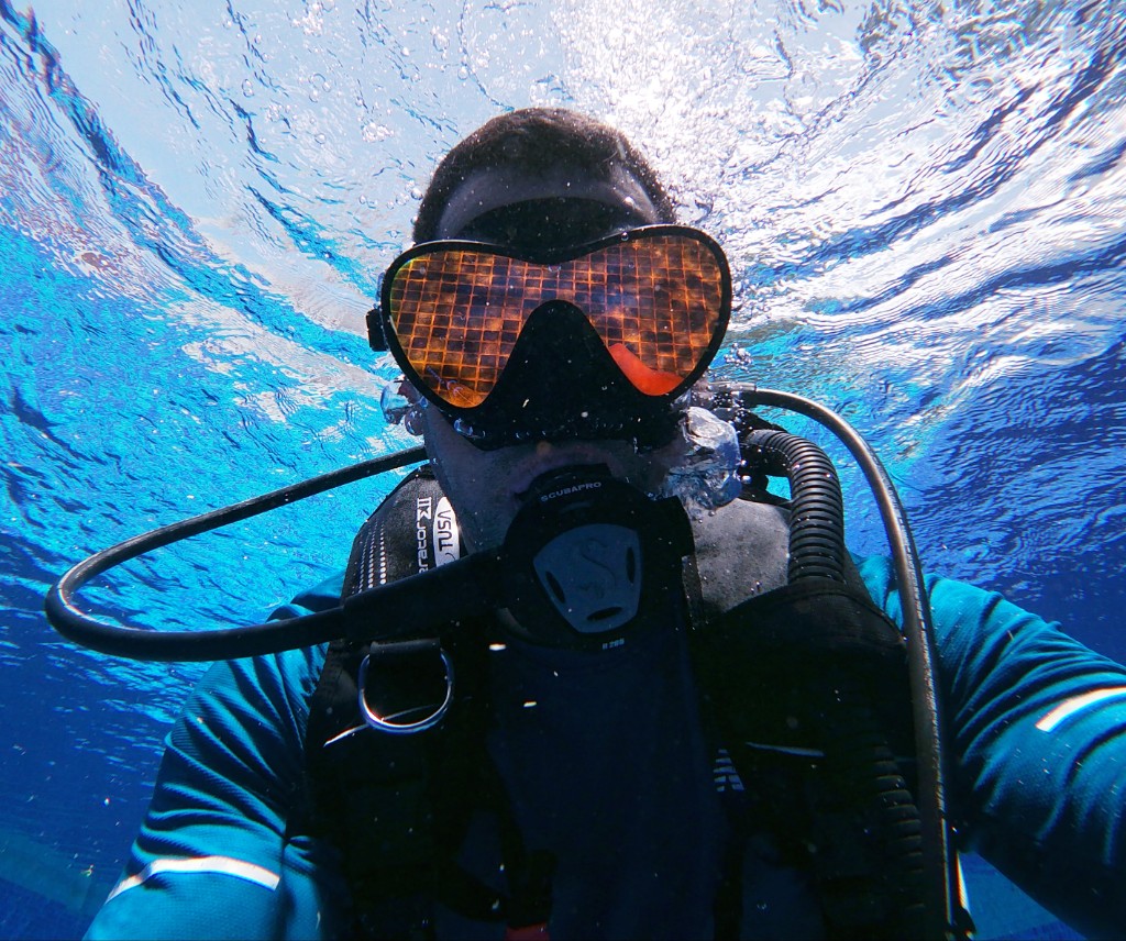 Buzo en agua clara, primer plano bajo el agua mirando hacia la superficie iluminada por el sol